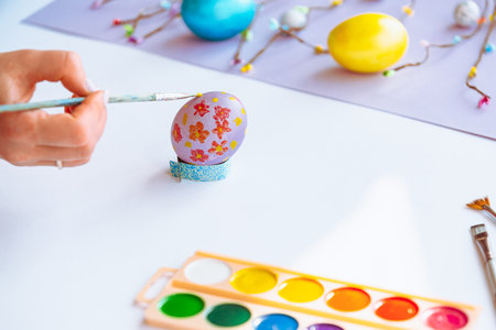 Woman hand painting easter egg with watercolors, preparation for egg hunt game. Happy easter congratulation symbol.の写真素材