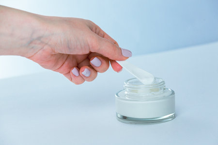 Female hand holding a jar of moisturizing cream on a white backgroundの写真素材