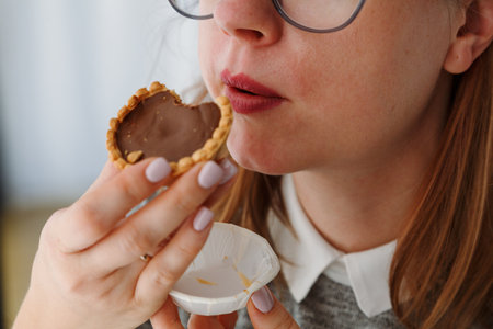 Woman eating sweet tarts with chocolate and snacks with sugar.の写真素材