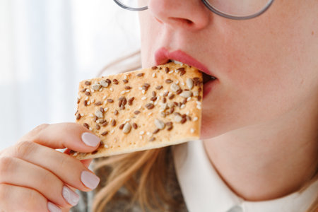 Close-up of womans mouth eating no sugar cookie with sesame seeds, pastry for dietary meal