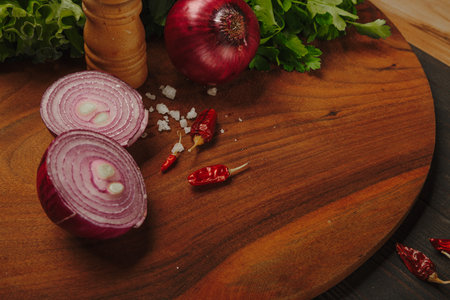 Chopped onion and red chili pepper on a wooden cutting board with salt, prepared to cook a meal.の写真素材