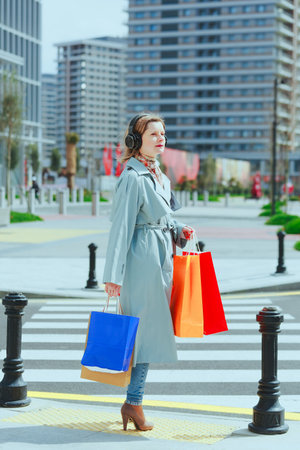 Woman with colorful shopping bags and headsets crossing the roadの写真素材