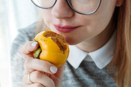 Close up of woman mouth eating persimmon, healthy snack on lunch time. Exotic fruit.の写真素材
