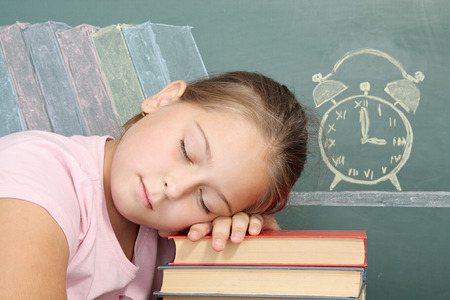 Tired schoolgirl asleep on textbooksの写真素材