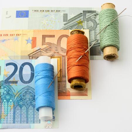 ?oncept. Renovation of European financial system. Colored thread and a needle for repair of Euro