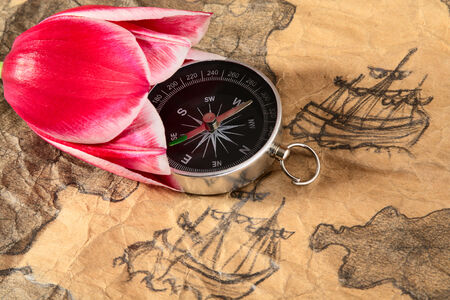 Compass in tulip on a old marine map with image of sailers