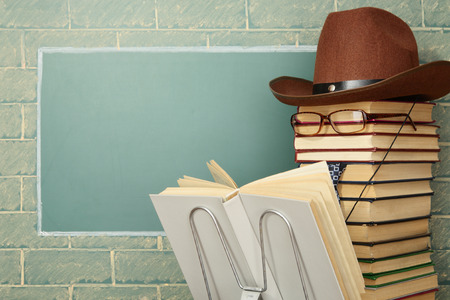Unusual jesting teacher reading book before blackboard with copy space