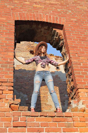 Attractive girl in torn jeans in window of old ruinsの写真素材