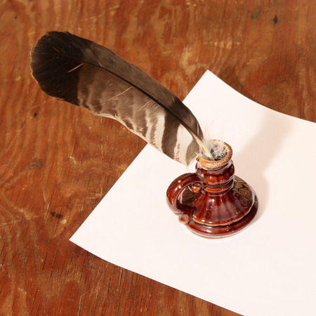 White sheet of paper and quill with inkpot on a wood backgroundの写真素材