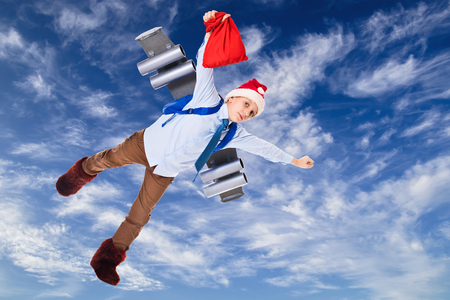 Young Santa Claus flying in the sky with presents for Christmas on a jet packの写真素材