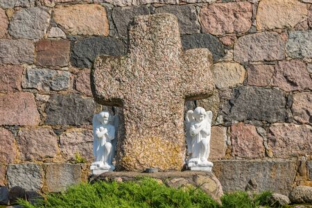 Angels near the stone cross on the background of a powerful wall