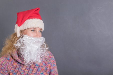 Cheerful adult woman trying on a Santa Claus beardの写真素材