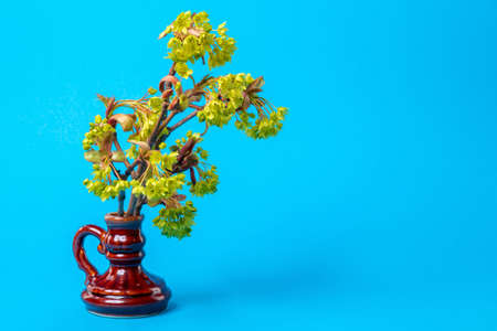 Twig of a blossoming tree in a vase on a blue background. Easter decoration
