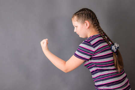 A schoolgirl girl full of determination threatens someone with her fist