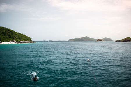 Beautiful view blue see, rough waves, and skyline with scuba diver floating on the sea in evening at Samaesarn Island, Chonburi Thailand.の写真素材