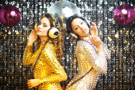 two beautiful sexy disco women in gold and silver catsuits dancing in a club setting. Useful for fashion, beauty, music and eventsの写真素材