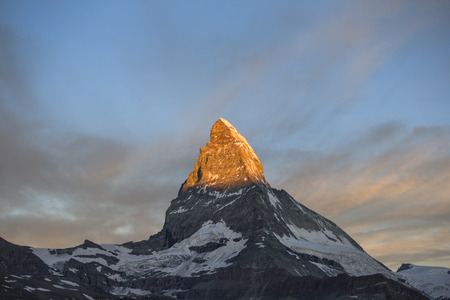 dawn, sunrise scene of the amazing matterhorn mountain in the Swiss Alps. the sky lights up in an incredible display of colour and the shadow lowers over the mountainの写真素材