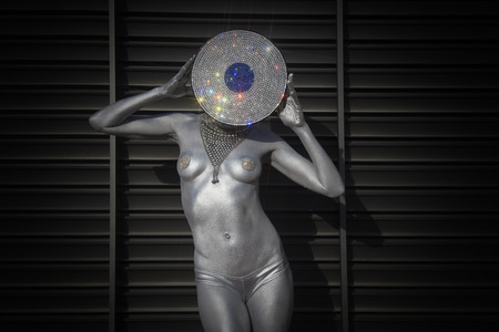 sexy disco woman painted in silver body paint with an amazing diamond crystal record vinyl as a headの写真素材