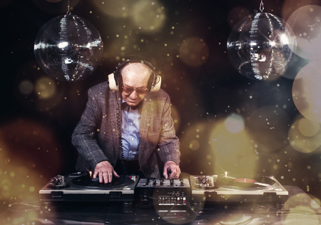 an amazing grandpa DJ, older man djing and partying in a disco settingの写真素材