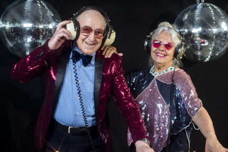 an amazing grandma and grandpa, older couple djing and partying in a disco settingの写真素材