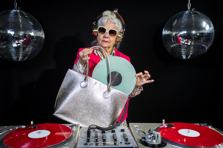 an amazing grandma DJ, older lady djing and partying in a disco settingの写真素材