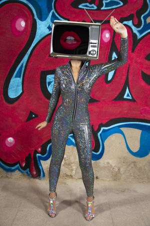 Tv head woman infront of the word love graffiti painted on a wall