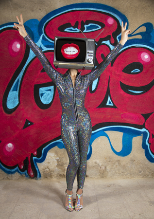 Tv head woman infront of the word love graffiti painted on a wallの写真素材