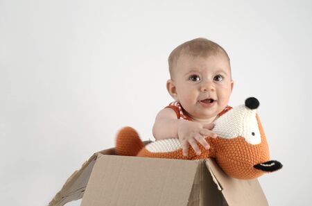 adorable small baby girl in a box with cuddly teddy bearsの写真素材