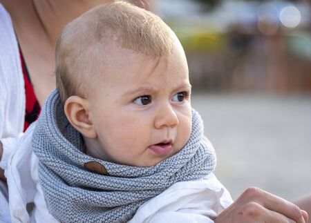 adorable small baby girl with expressive face, sitting with her mum