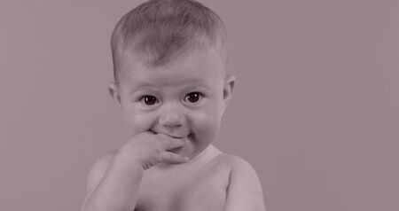 adorable small baby girl with expressive face, against plain colour backgroundの写真素材