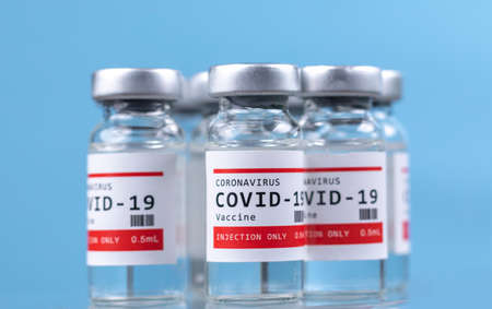 Glass vials of the covid-19 vaccine on blueの写真素材