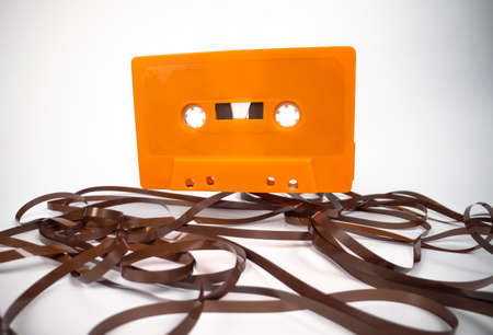 An orange cassette with magnetic tape on floorの写真素材