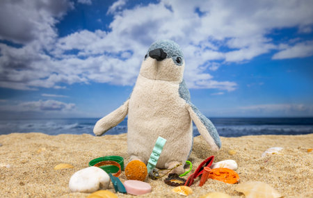 A toy penguin with trash on beach