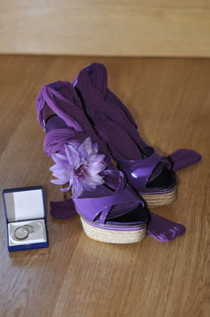 Violet heels with flower and wedding rings on wooden floorの写真素材
