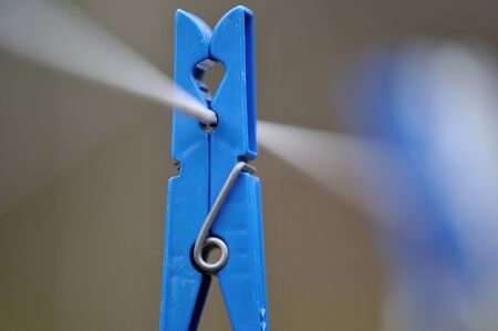 Colored clothespins hang on a cord outside of homeの写真素材