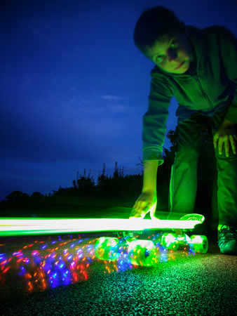 Young boy holding lighting skateboard in motionの写真素材