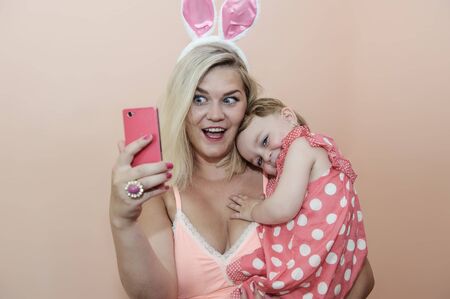 Mother and daughter making selfie. Young mother. Pink color photo