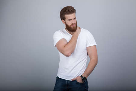 Serious thoughtful male with ginger beard, dressed casually, focused somewhere, isolated over white backgrounの写真素材