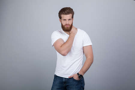 Serious thoughtful male with ginger beard, dressed casually, focused somewhere, isolated over white backgrounの写真素材