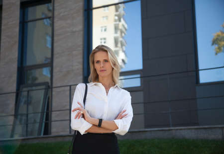 Business woman in a suit crossed her arms over her chest against of office buildingの写真素材