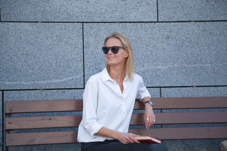 happy woman in sunglasses sitting with bookの写真素材