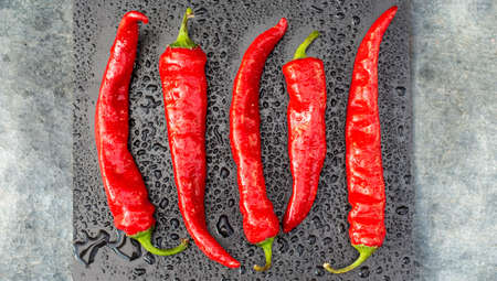 Red hot chili peppers wet in drops of water on a black background top viewの写真素材