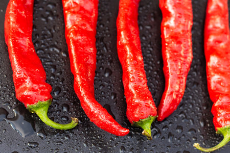 Red hot chili peppers pure in drops of water on a black background close upの写真素材