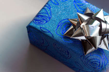 Beautiful sparkling gift box of blue color with the image of roses with a silver bow on top on a white backgroundの写真素材
