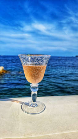 A glass of chilled white wine by the sea. Vacation conceptの写真素材