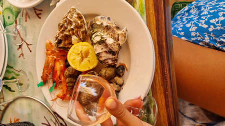 Plate of seafood on the table in front of a girl on vacationの写真素材