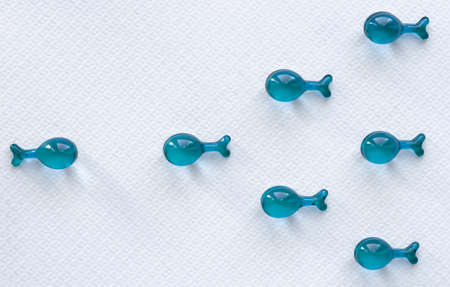 Capsules in the form of fish on a white background. Swim against the current. One against all. The movement of the fish. Sperm movementの写真素材