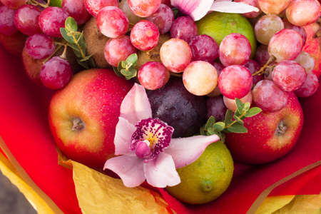 Fruity bouquet of red apples with plums, grapes, pomegranate, lime and pink orchids.の写真素材