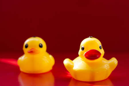 Yellow rubber duck with big lips on a red background. Natural beauty. Artificial made lips. Botox lips. Duck lips.のeditorial素材