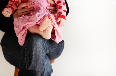 little baby-girl in pink dress sitting on her mother's handsの写真素材